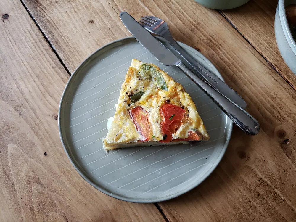 Fetta di frittata su un piatto, con il taglio che mostra l'interno morbido